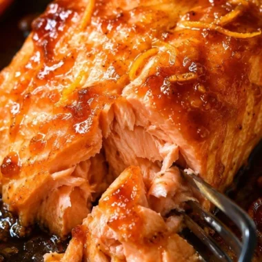 Baked salmon drizzled with orange sauce, garnished with fresh herbs