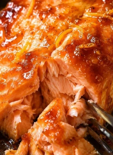 Baked salmon drizzled with orange sauce, garnished with fresh herbs