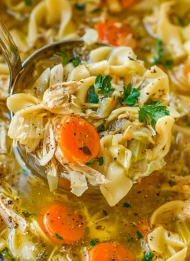 Bowl of cozy chicken noodle soup garnished with herbs and vegetables