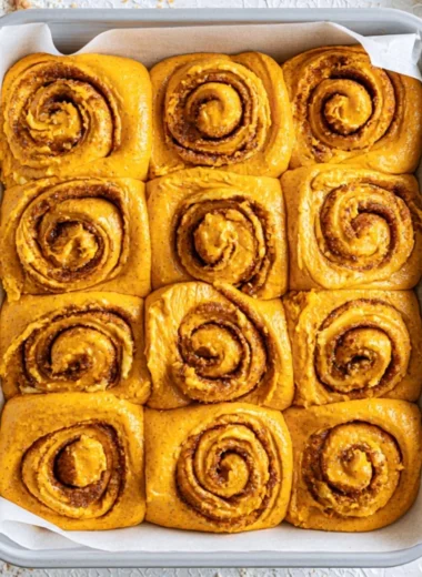 Delicious pumpkin cinnamon rolls topped with cream cheese icing, perfect for fall.