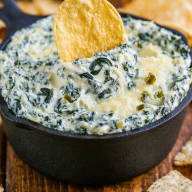 Warm and creamy spinach artichoke dip served in a bowl with tortilla chips
