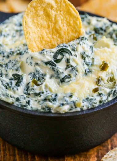 Warm and creamy spinach artichoke dip served in a bowl with tortilla chips