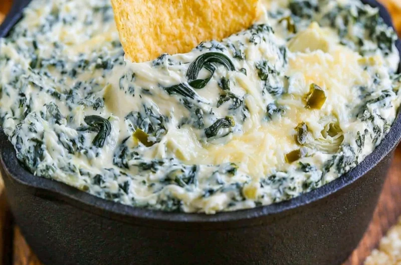 Warm and creamy spinach artichoke dip served in a bowl with tortilla chips