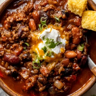 Bowl of cozy best chili recipe topped with cheese and herbs