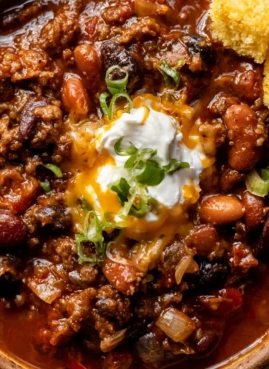 Bowl of cozy best chili recipe topped with cheese and herbs