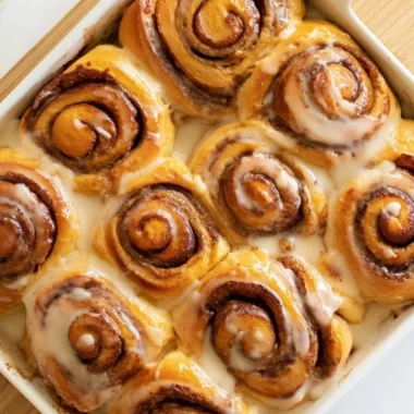 Cozy heavy whipping cream cinnamon rolls on a plate, drizzled with icing.