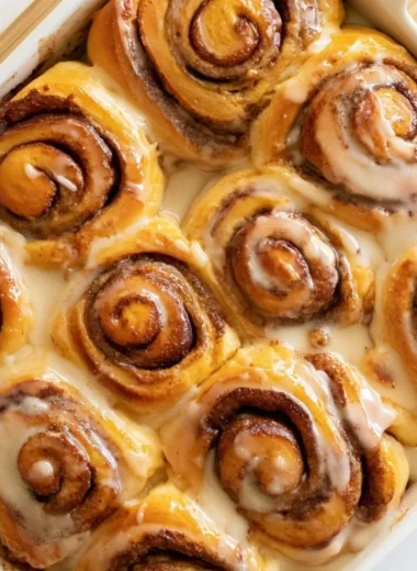 Cozy heavy whipping cream cinnamon rolls on a plate, drizzled with icing.
