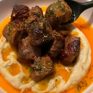 Delicious Cowboy Butter Steak Bites topped with caramelized onions on a plate.