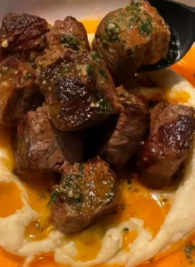 Delicious Cowboy Butter Steak Bites topped with caramelized onions on a plate.