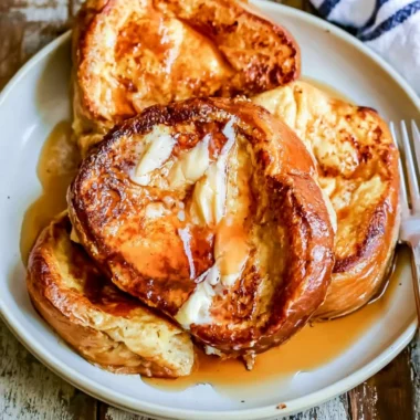 Delicious French toast topped with syrup and berries on a plate