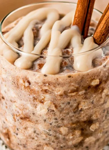 Bowl of cinnamon roll overnight oats topped with cinnamon and nuts