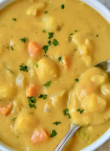 Bowl of creamy German potato soup garnished with herbs and bacon