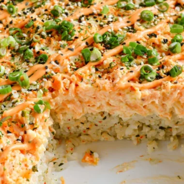Delicious salmon sushi bake topped with creamy sauce and fresh ingredients.