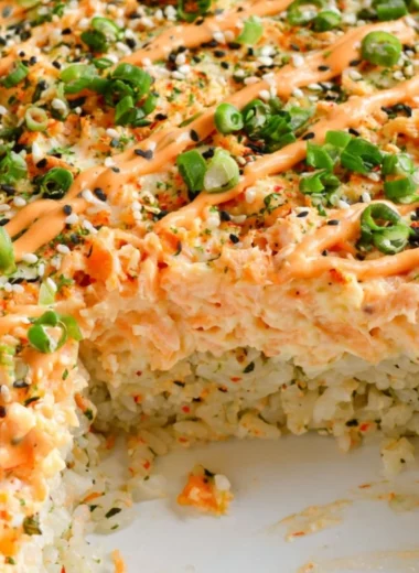 Delicious salmon sushi bake topped with creamy sauce and fresh ingredients.