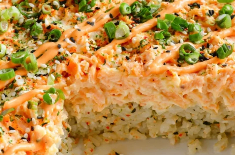 Delicious salmon sushi bake topped with creamy sauce and fresh ingredients.